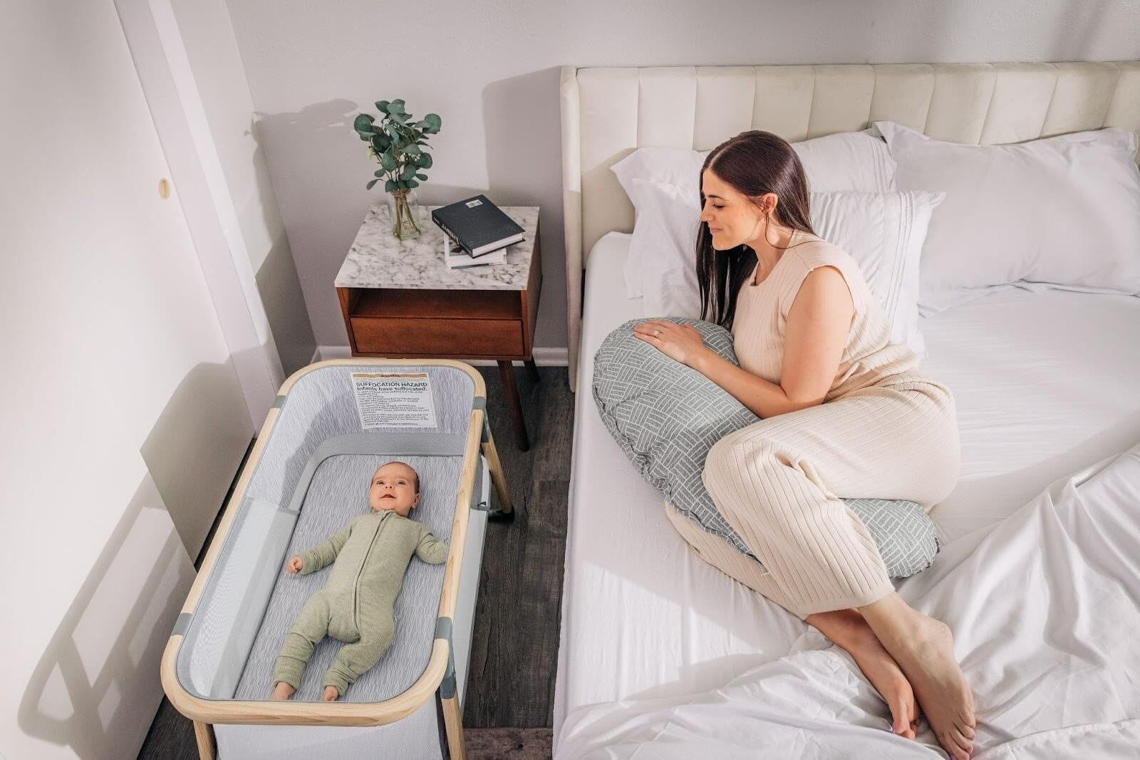 baby in bassinet with postpartum mom on bed
