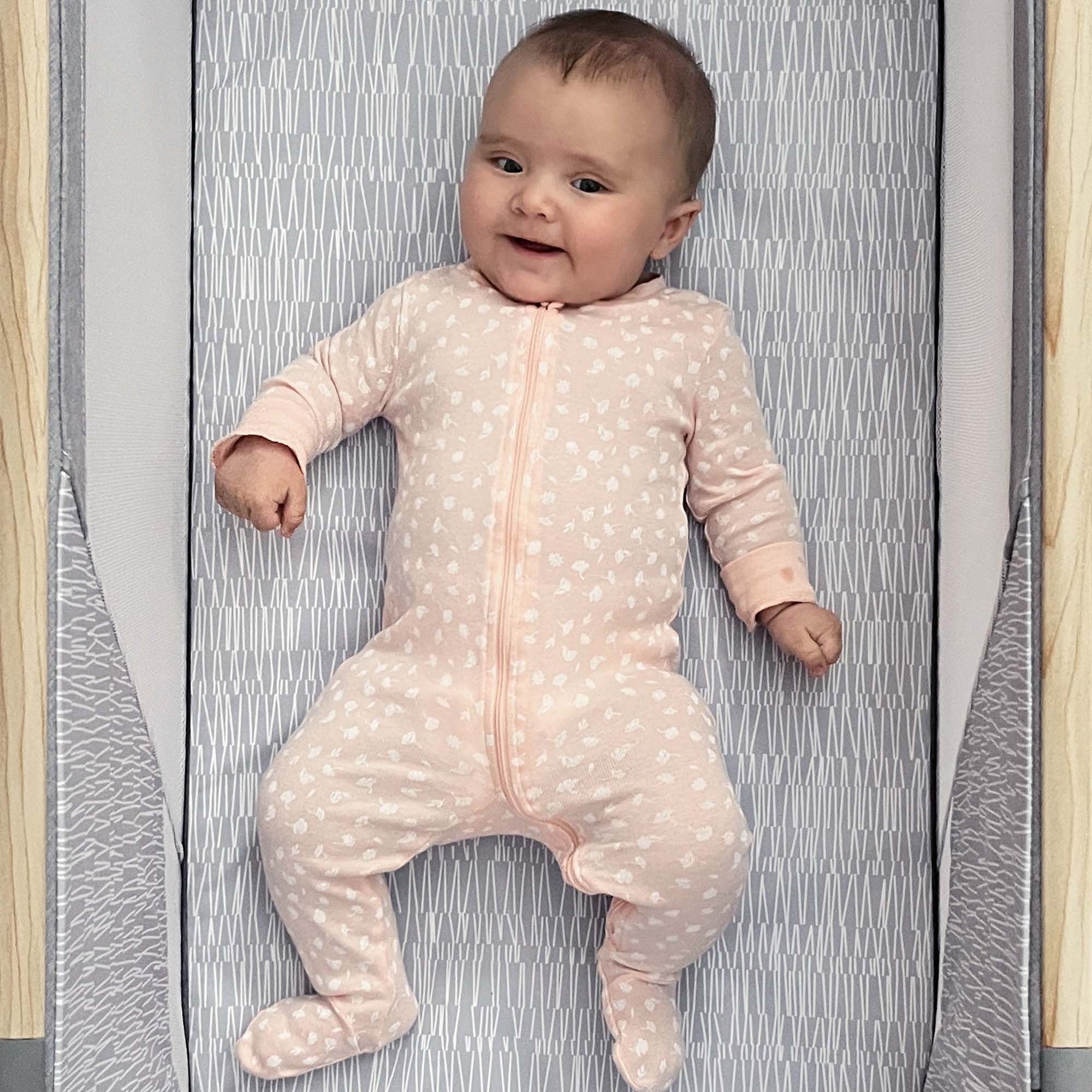 baby in pink pajamas laying in bassinet