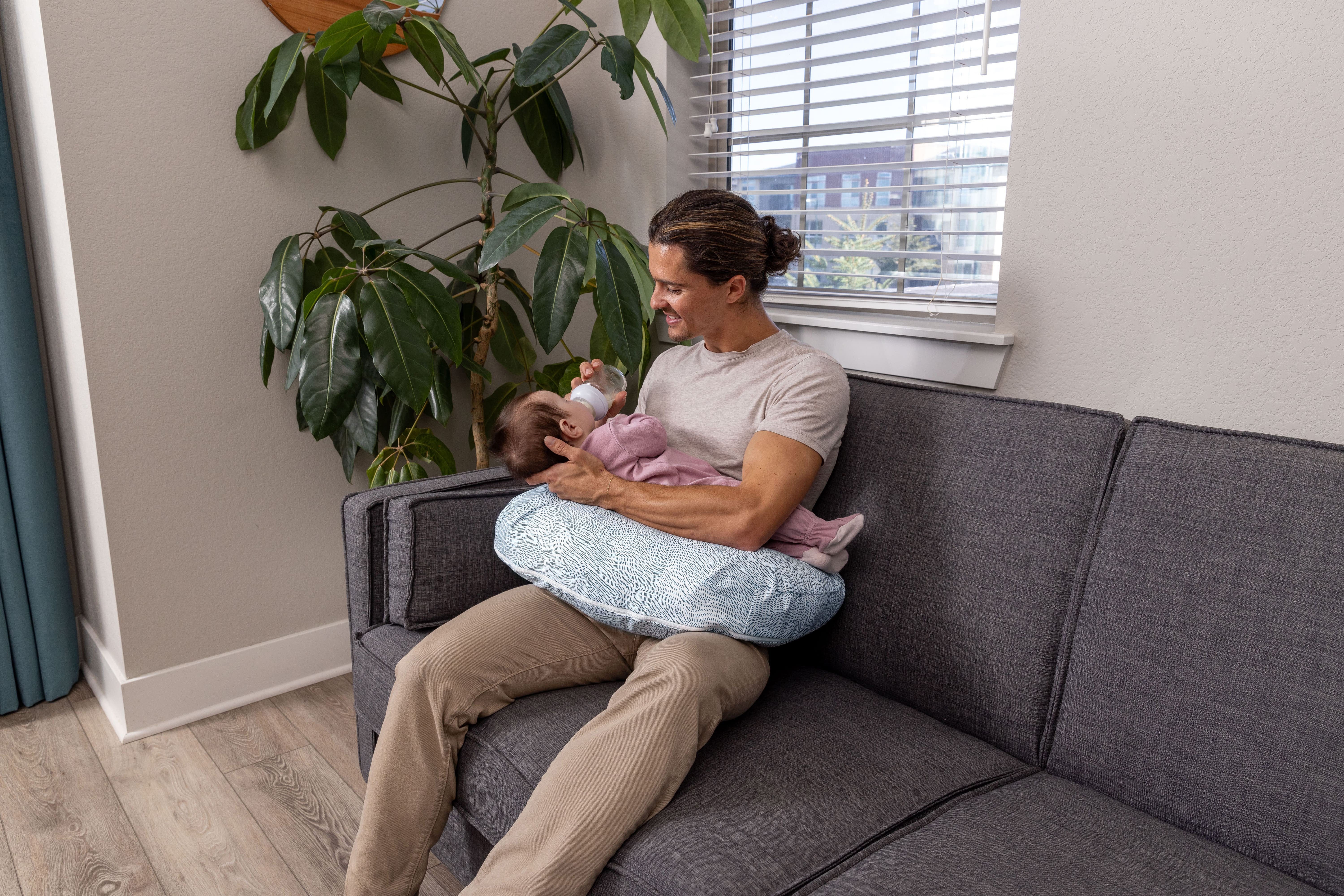 dad bottle feeding baby with nursing pillow