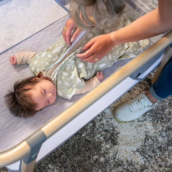 Sleeping baby getting zipped up by their parent into the Boppy wearable blanket